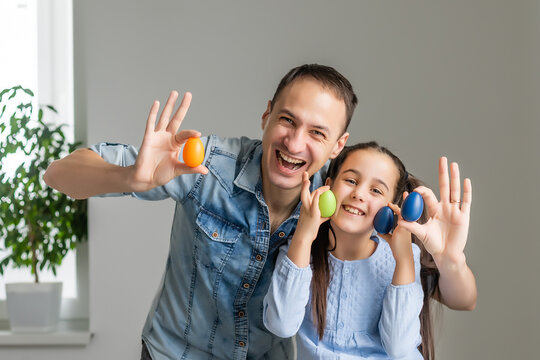father and daughter paint eggs with colors. Have fun. Happy family is preparing for Easter.