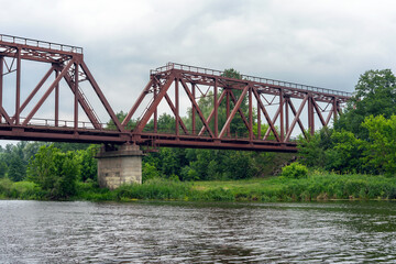 Fototapeta na wymiar Old rusty railway bridge over the river