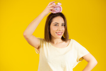 Portrait of cheerful young woman holding alarm clock isolated over yellow background