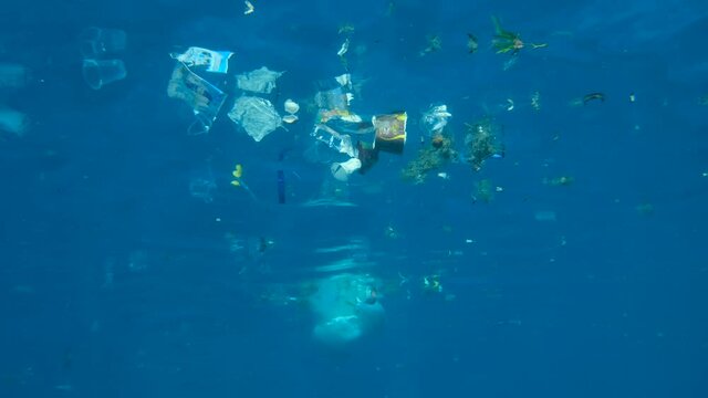 Slow motion, Massive plastic and other debris slowly drifts under surface of the blue ocean in the sun lights. Plastic garbage environmental pollution problem. Plastic pollution of the Red Sea