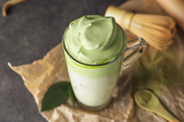 Cup of tasty dalgona matcha latte on dark background, closeup