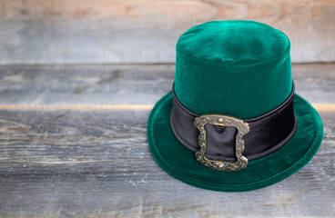 Green leprechaun hat with gold buckle on rough wood background. concept of St Patricks Day. mockup. Copy text
