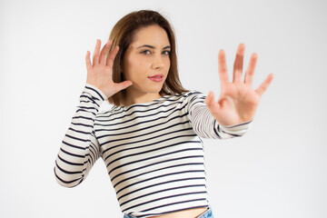 Young beautiful woman wearing casual striped t-shirt over isolated white background Moving away hands palms showing refusal and denial with afraid and disgusting expression. Stop and forbidden.