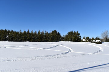 Snowmobile tracks in the snow under a blue sky, Québec