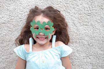 Closeup portrait of a happy preteen caucasian girl in an emerald leprechaun glasses in the form of clover. St. Patrick's Day concept