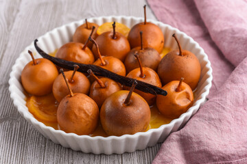 Mini pears in caramel and vanilla sauce on the wooden table