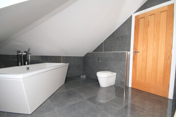 marble tiled modern bathroom with bath and toilet