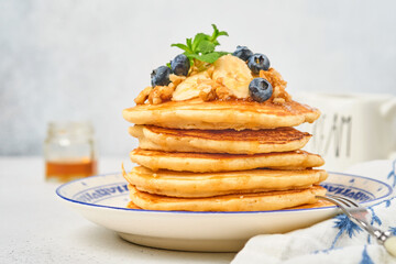 Pancakes with banana, walnut, honey and caramel for a breakfast. Selective focus