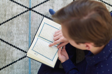 Young muslim man reading Quran during Ramadan