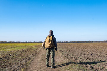 Male traveler with tactical and militari equipment walk alone in sunny day