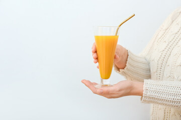 Woman with glass of healthy turmeric drink on light background