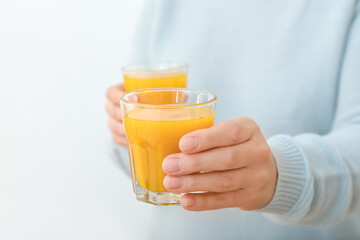 Woman with glasses of healthy turmeric drink on light background