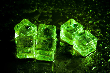 Green ice cubes reflection on black table background.