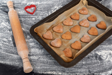 Freshly baked homemade gingerbread heart shaped cookies next to wooden rolling pin