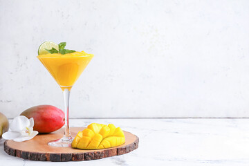 Glass of tasty mango margarita on light background