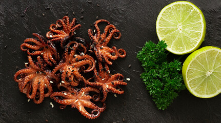 Grilled mini  octopuses,  baby, dish, on a black background, top view, horizontal, no people, © Gala_Didebashvili