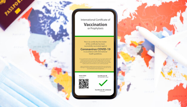 A smartphone with a certificate of vaccination against the Covid-19 is arranged on a blurred World Map. Travel concept during the Coronavirus pandemic. - Powered by Adobe