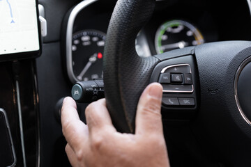 Unrecognizable man driver activating the adaptive cruise control or steering assistantใ