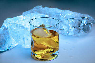 an ice cold frosty glass of liquor such as scotch or whiskey on blocks of ice with dramatic lighting