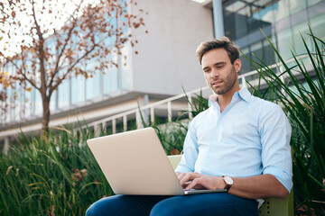 Young businessman working on a laptop outside of an office