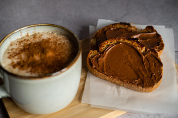 Breakfast of toasts with cocoa cream and cup of coffee with milk and cinnamon