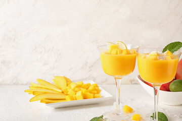 Glasses of mango margarita on light background
