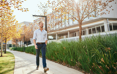 Young businessman walking along a footpath by an office