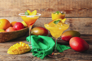 Glasses of mango margarita on wooden background