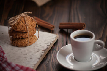 A cup of aromatic black coffee. Morning espresso or Americano coffee for breakfast in a beautiful cup. Cinnamon sticks. Wooden background. Russian gingerbread. 