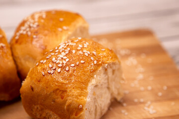 Close up homemade food baking concept. Fresh hot soft fluffy ginger golden brown sesame seeds buns pie bread dessert pastry on cutting board. Bakery products, image with copy space.