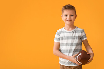 Cute little boy with rugby ball on color background