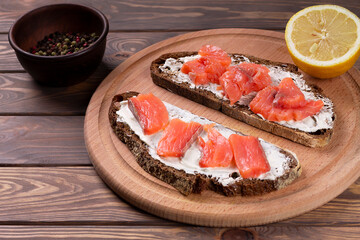Smoked salmon with lemon and cream cheese on black bread. Traditional Scandinavian cuisine.