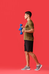Sporty young man training with dumbbells on color background