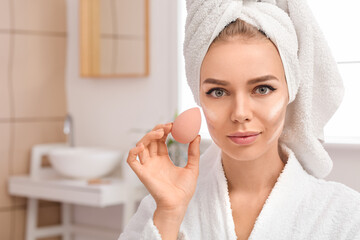 Beautiful young woman applying contouring makeup at home