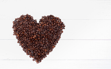 Roasted coffee beans in the heart shape On a white plank table, coffee lover,  background, coffee