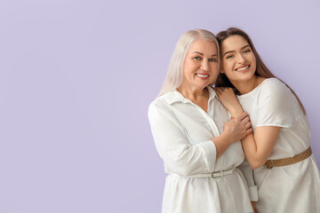 Portrait of young woman and her mother on color background