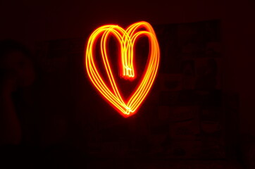 Heart shape made with red light in long exposure with black background. Light painting photography. Valentine's day and love concept. Vibrant heart outline.