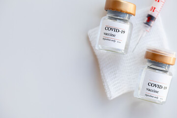 Two vials with COVID-19 vaccine on sterile gause swab. Syringe in the background. Flat lay