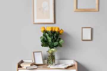 Vase with beautiful yellow roses on chest of drawers in interior of room