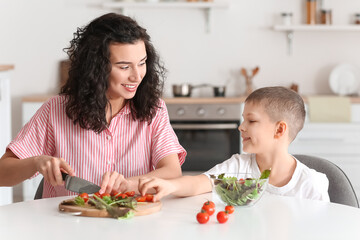 Happy woman and her little son cooking in kitchen