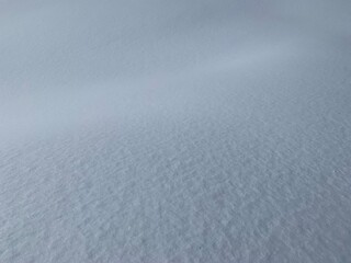 Snow Covered Field On A Sunny Day. Wavy surface of clean fresh snow. Snowy ground. Winter background with a snowdrift. Perfect for Christmas and New Year design.