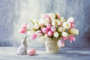 Easter decoration and tulips bouquet in a vase on a blue background. Easter concept.
