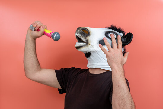 person wearing a cow mask singing into a microphone