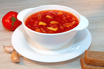 Borscht soup with meat in a white bowl on a wooden table