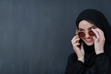 Young muslim businesswoman in traditional clothes or abaya using smartphone