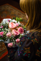 Woman looking on bunch. A woman admires a gorgeous bouquet. The blonde looks at flower arrangement. Congratulations on Women's Day, Mother's Day, Birthday. Vertical. Dark. Florist. Selective focus