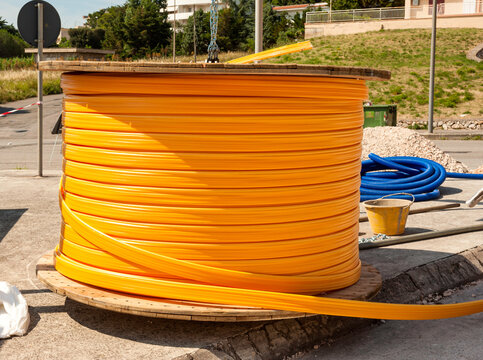 Roll of outdoor fiber optic signal shielded cable. Wooden Coils of powerful orange telecommunications wire