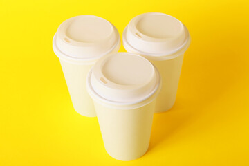 Blank takeaway cups on color background