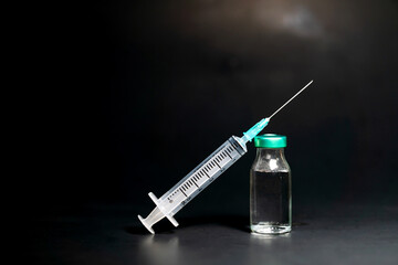 Potential trials stage concept on black background. Close up Vials with sterile needle syringe....