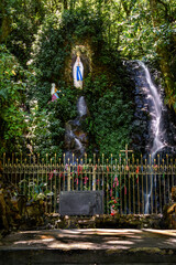Sanctuary in the forest with religious divinity, small waterfall between the rocks, green cover around - 419670689